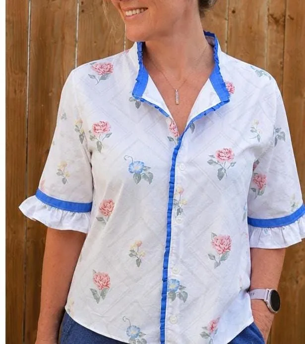White floral blouse with blue ruffle trim worn outdoors